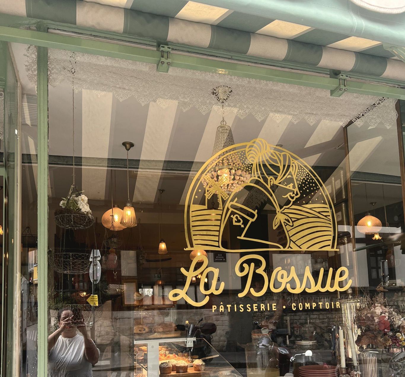 A neighbourhood pâtisserie storefront in Paris — La Bossue, with its striped awning and gold sign