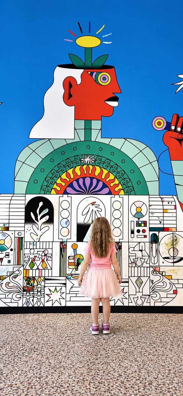 A child in a pink tutu seen from behind facing a huge colourful line-art mural at the Grand Palais Palais des Enfants, Paris