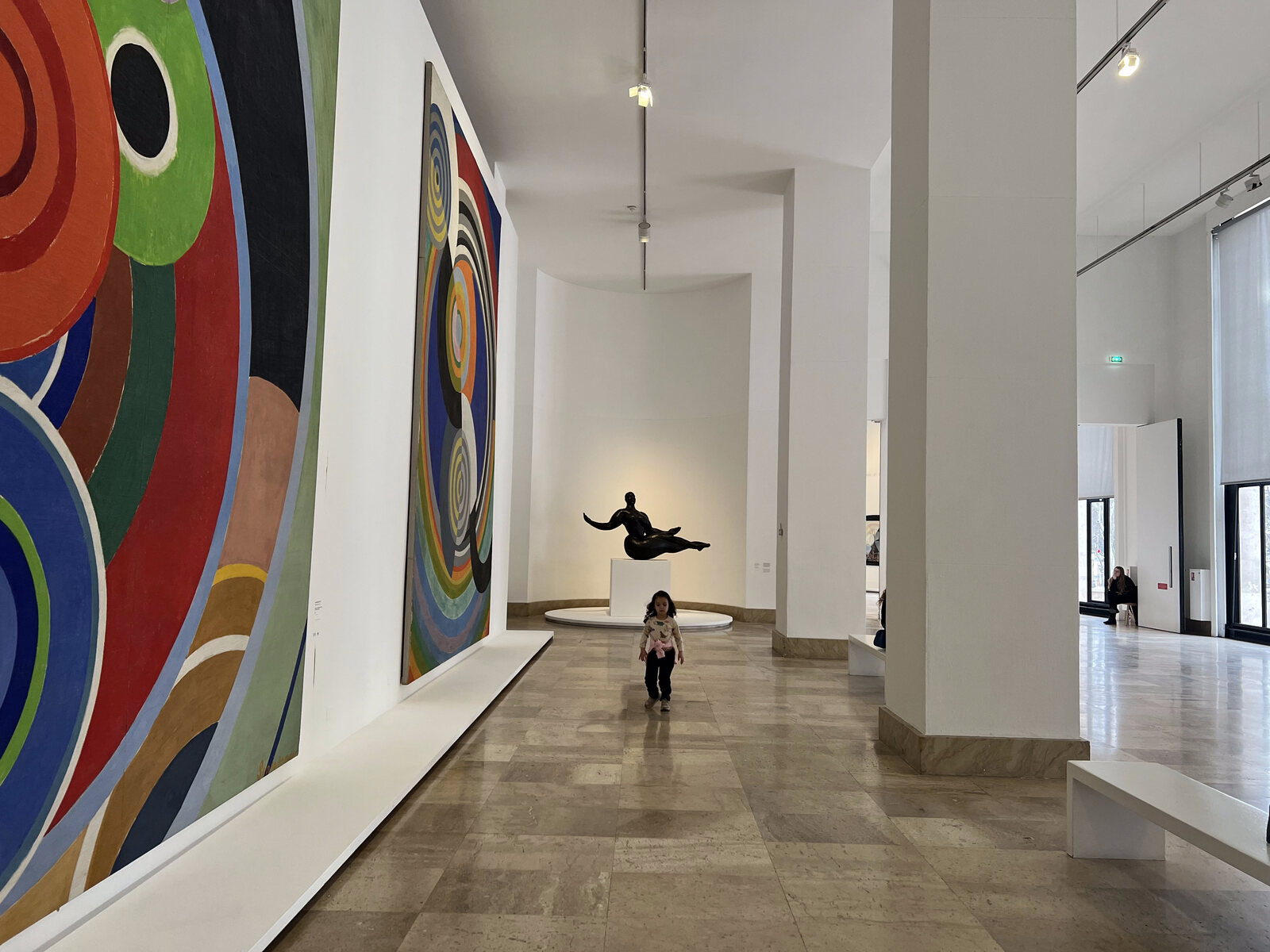 A child looking at bold, colourful modern-art murals in a Paris gallery
